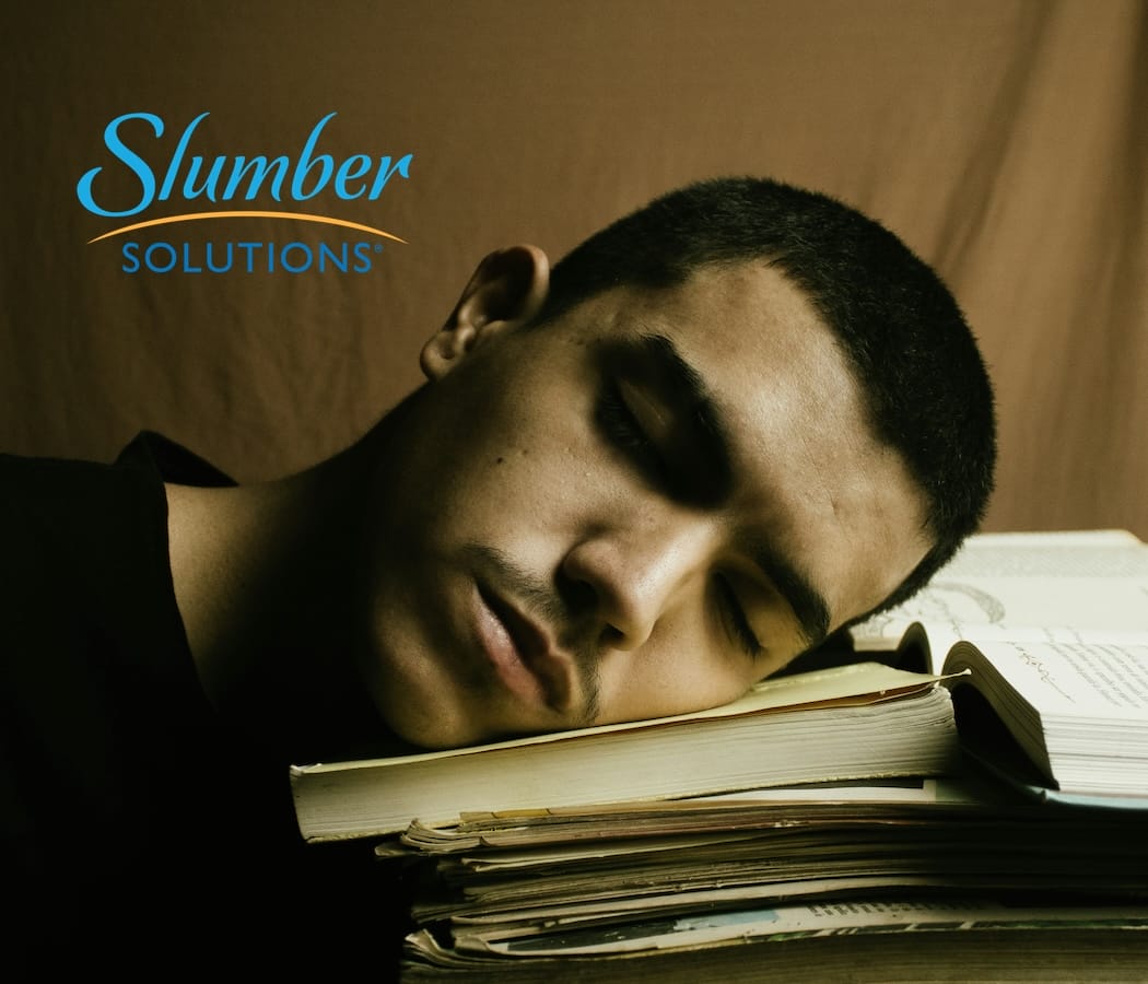 male college student sleeping on books