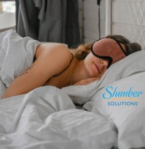 Woman in bed wearing sleep mask.